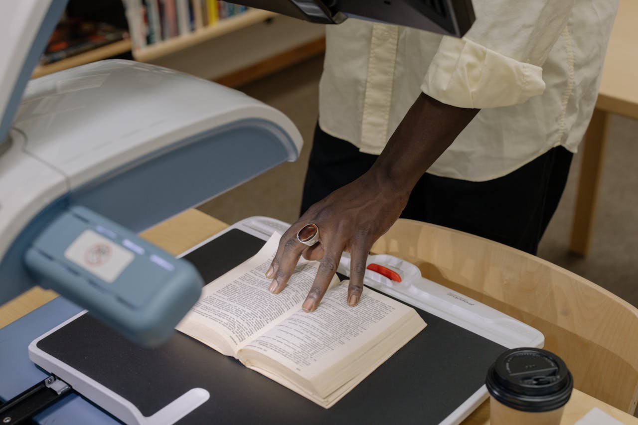 services-03 An anonymous individual scans a book in a library setting, emphasizing technology and research.