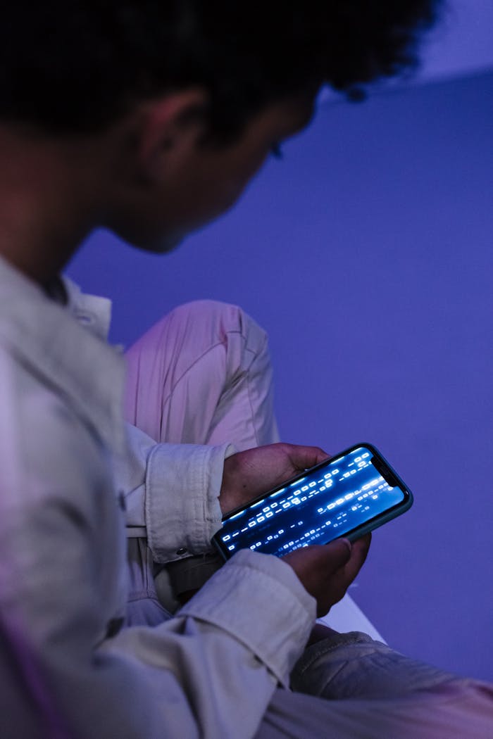 Teenager casually browsing on smartphone indoors, focused on screen.